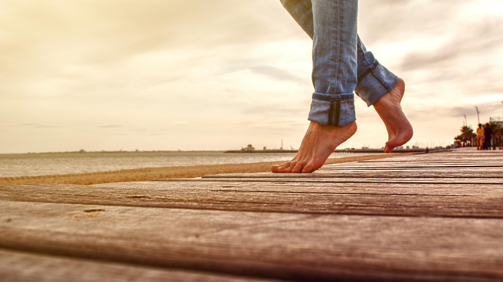 Bare feet walking confidently along a boardwalk